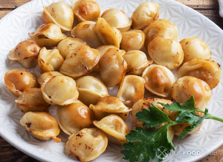 2021-09-08-4r1uiv-traditional-fried-pelmeni-ravioli-dumplings-filled-with-meat-on-plate-russian-kitchen-wooden-rustic-table-copy-space