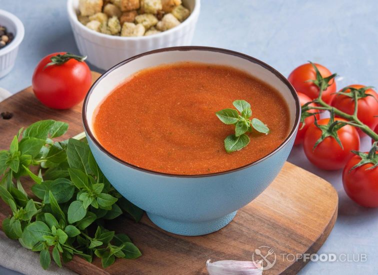 2021-09-29-pef53k-tomato-creme-soup-with-crumbs-and-basil-on-blue-background-close-up
