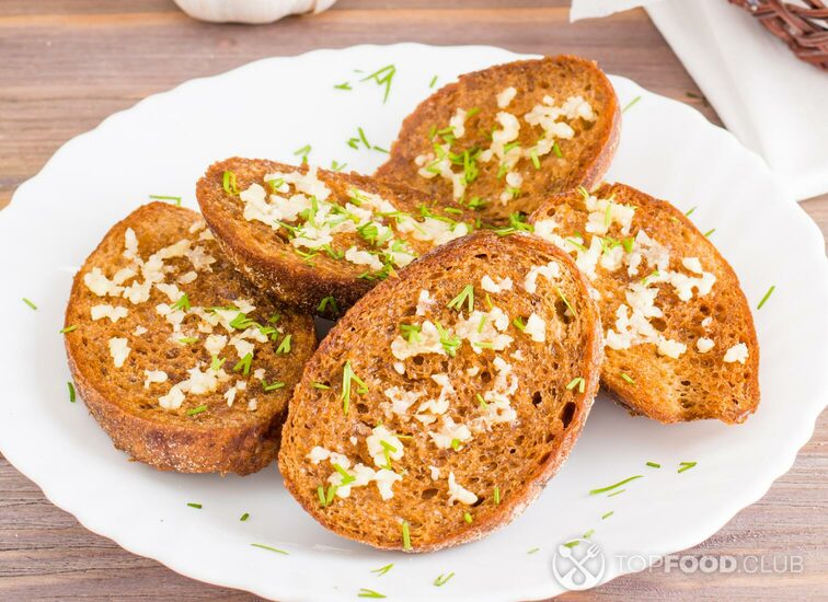 2021-11-04-gokxu0-fresh-rye-garlic-croutons-with-dill-on-a-plate-and-buns-in-a-basket-on-a-wooden-table