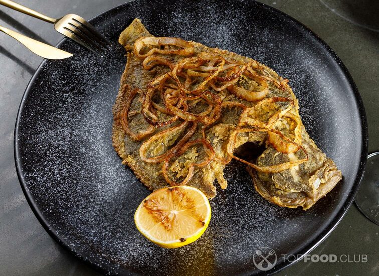 2021-11-12-s3n52j-fried-flounder-with-onion-and-lemon-on-a-black-clay-plate