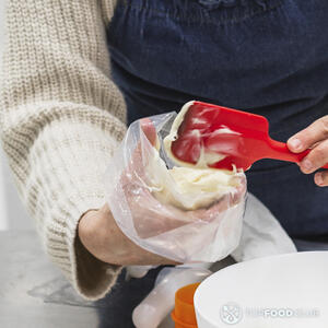 накладывает тесто в кондитерский мешок