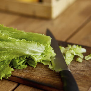 Нарезает листья салата
