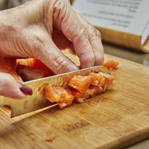 нарезает рыбу кубиками