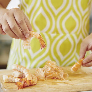 чистит креветки