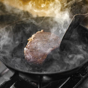 готовит стейк