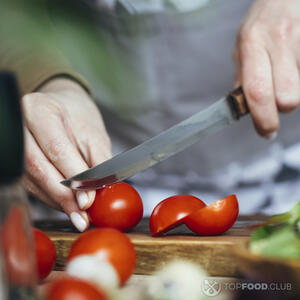 нарезает помидоры черри