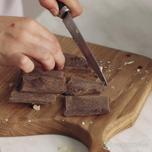 нарезает черный шоколад