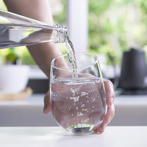 наливает воду в стакан