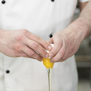 разбивает куриное яйцо