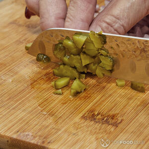 нарезает маринованные огурцы