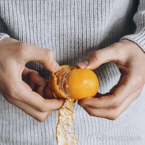 чистит мандарин