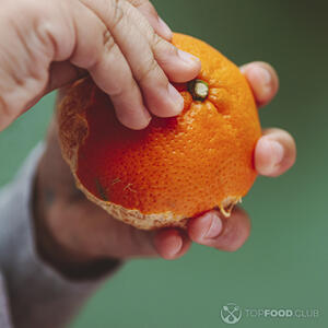 чистит апельсин