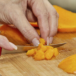 нарезает манго на кубики