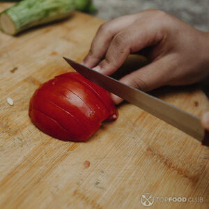 нарезает помидор