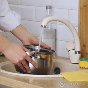 наливает воду в кастрюлю