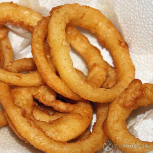 Выкладывайте обжаренные луковые кольца на бумажное полотенце, чтобы удалить избыток масла. Затем положите их на блюдо и подавайте к столу горячими.