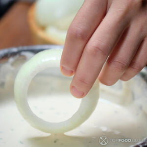 Обмакивайте луковые кольца, по одному, в подошедший кляр, стряхивая лишнее тесто