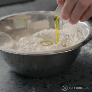 В середине муки сделайте лунку, влейте оливковое масло.