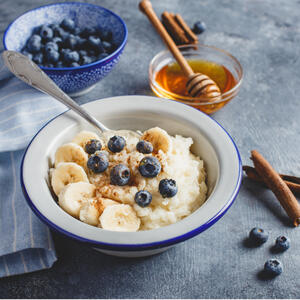 Перемешайте и подавайте молочную рисовую кашу порционно, посыпав молотой корицей, украсив свежими ягодами черники и ломтиками банана