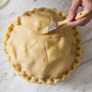 Смажьте верхнюю часть пирога взбитым яйцом