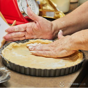 Уложите пласт песочного теста в форму для круглого пирога