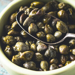 Каперсы выложите из баночки в дуршлаг, дайте стечь маринаду