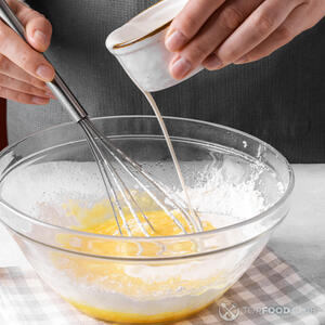 В миску с мукой и яйцами постепенно влейте молоко, взбивая все венчиком. 