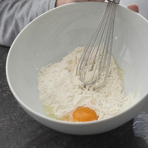 Муку просейте в большую миску, вбейте яйца