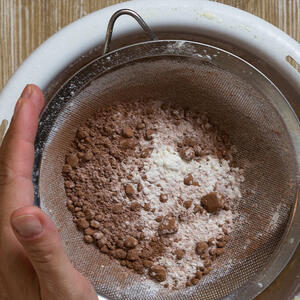 В другую миску просейте какао-порошок, пищевую соду, всыпьте муку и все перемешайте венчиком или вилкой. 