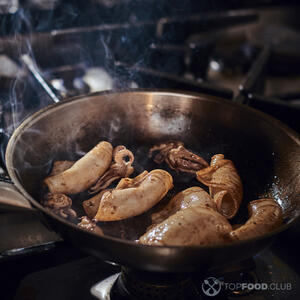 Через 1 минуту в сковороду добавьте целые тушки мини-кальмаров