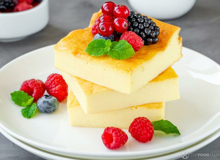 2021-09-15-b1ix7c-homemade-cottage-cheese-casserole-with-fresh-berries-and-mint-on-top-on-a-white-plate-healthy-breakfast-vertical-copy-space