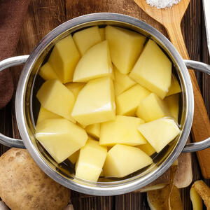 Wash the potatoes under running water, then peel and cut in half
